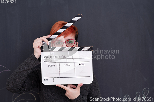 Image of redhead woman holding clapper on black background