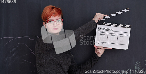 Image of redhead woman holding clapper on black background