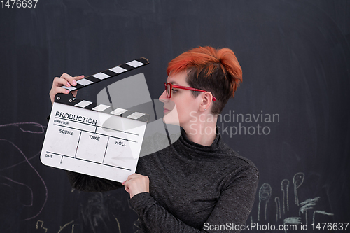 Image of redhead woman holding clapper on black background