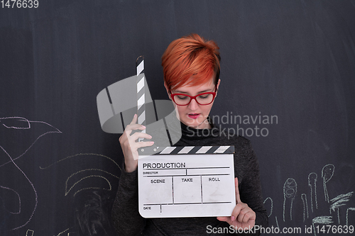 Image of redhead woman holding clapper on black background