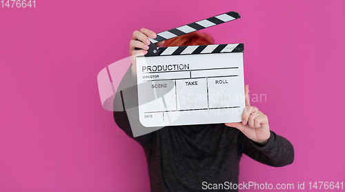 Image of redhead woman holding movie  clapper on pink background