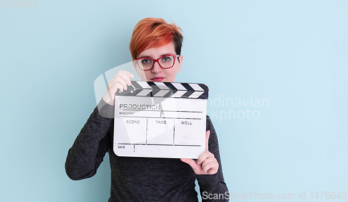 Image of redhead woman holding movie  clapper on cyan background