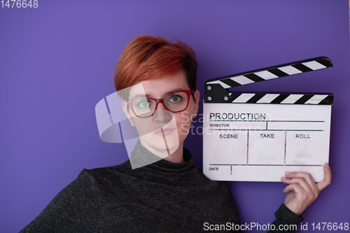 Image of redhead woman holding movie  clapper on purple background