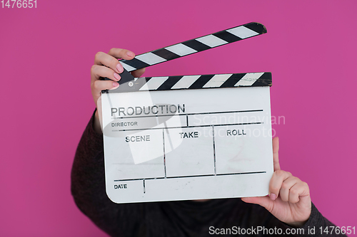 Image of redhead woman holding movie  clapper on pink background