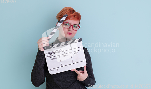 Image of redhead woman holding movie  clapper on cyan background