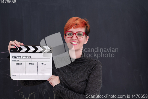 Image of redhead woman holding clapper on black background