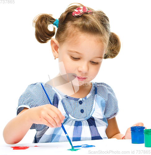 Image of Little girl is painting with gouache