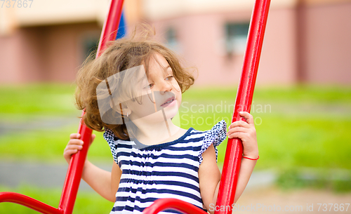 Image of Young happy girl is swinging in playground