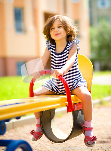 Image of Young happy girl is swinging in playground