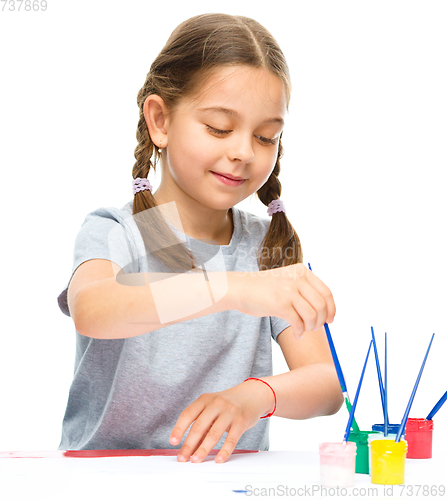 Image of Little girl is painting with gouache