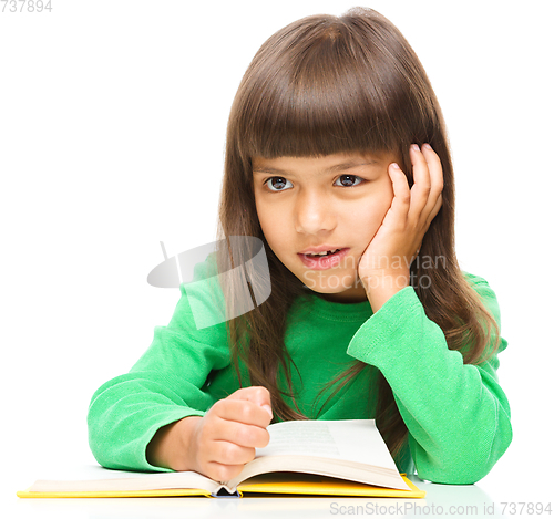 Image of Young girl is daydreaming while reading book