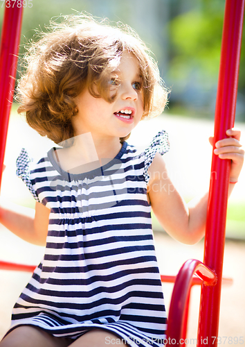 Image of Young happy girl is swinging in playground