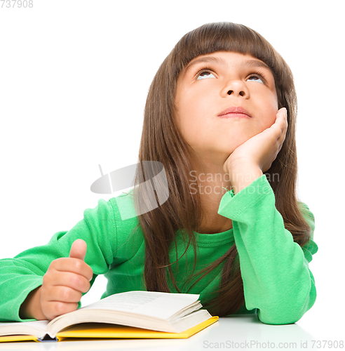 Image of Young girl is daydreaming while reading book