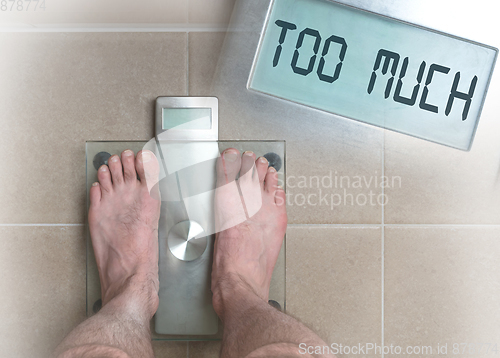 Image of Man\'s feet on weight scale - Too much
