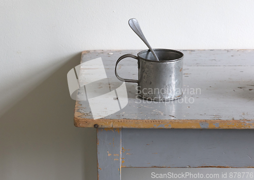 Image of Very old metal cups and plates on a wooden table