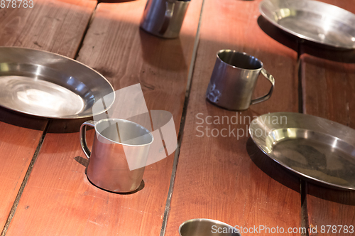 Image of Very old metal cups and plates on a wooden table