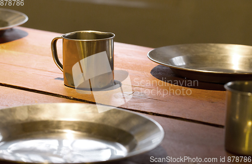 Image of Very old metal cups and plates on a wooden table