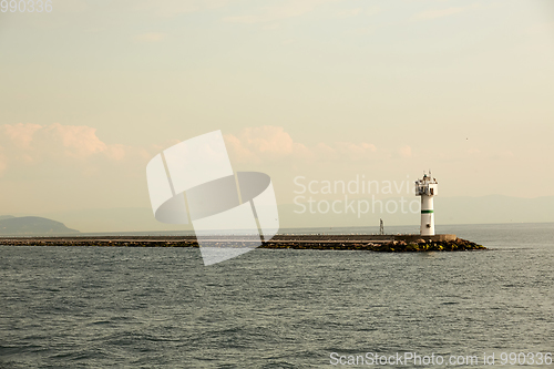 Image of Beautiful seascape with lighthouse. Calm sea and a lighthouse on the pier. Small beacon in the endless sea. Landscape and beacon. Lighthouse