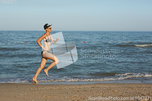 Image of Sexy and happy beautiful woman in bikini running on the beach. In a cap with the inscription queen. Film effect.