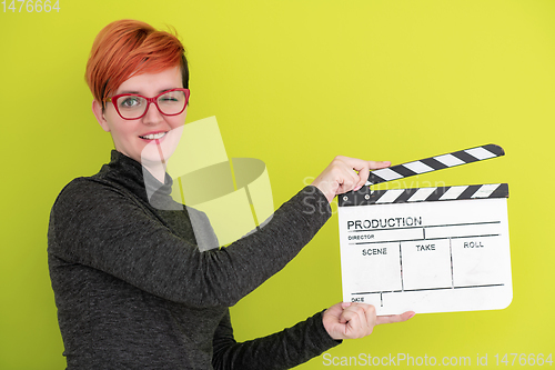Image of redhead woman holding movie  clapper on green background
