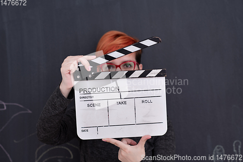 Image of redhead woman holding clapper on black background