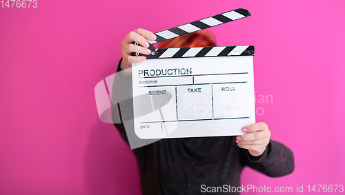 Image of redhead woman holding movie  clapper on pink background