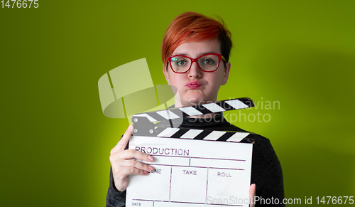 Image of redhead woman holding movie  clapper on green background