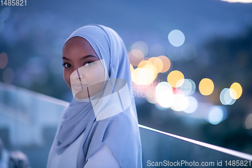 Image of African  modern Muslim woman in night at balcony