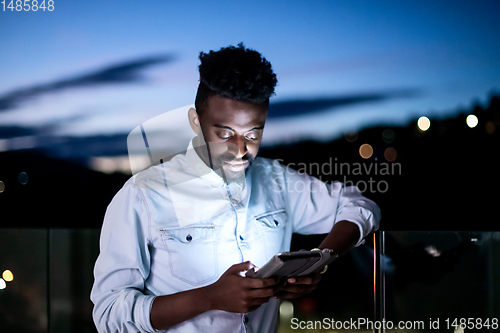 Image of Young  Afro man on street at night using tablet computer