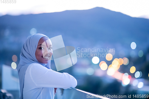 Image of African  modern Muslim woman in night at balcony