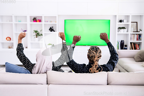 Image of African Couple Sitting On Sofa Watching TV Together