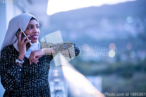 Image of Young Muslim woman on  street at night using phone