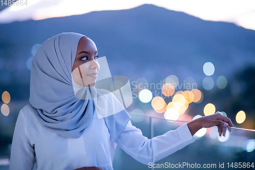 Image of African  modern Muslim woman in night at balcony