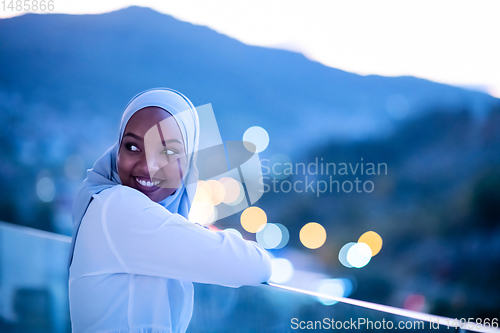 Image of African  modern Muslim woman in night at balcony