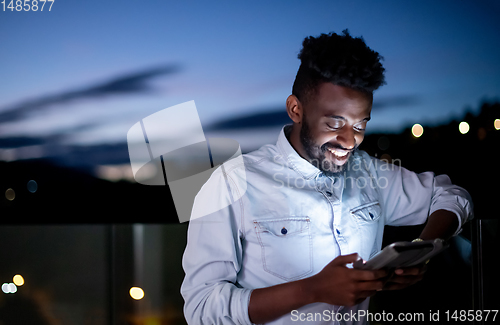 Image of Young  Afro man on street at night using tablet computer