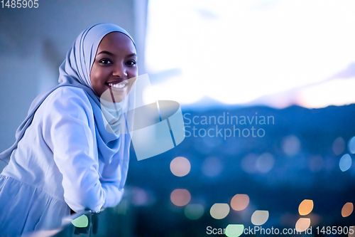 Image of African  modern Muslim woman in night at balcony