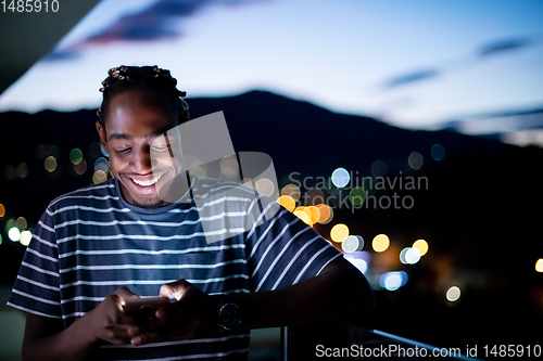 Image of Young  Afro man on  street at night using phone