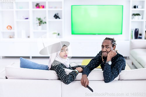 Image of African Couple Sitting On Sofa Watching TV Together