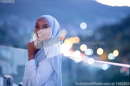 Image of African  modern Muslim woman in night at balcony