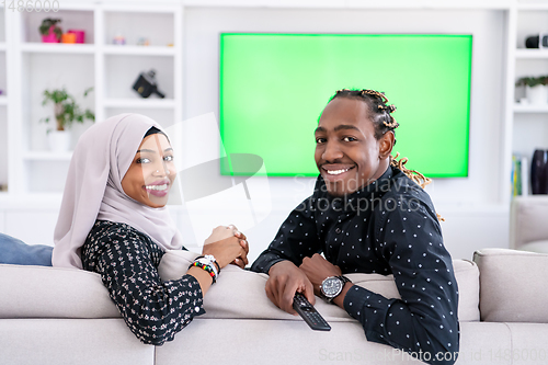 Image of African Couple Sitting On Sofa Watching TV Together