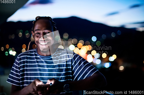 Image of Young  Afro man on  street at night using phone