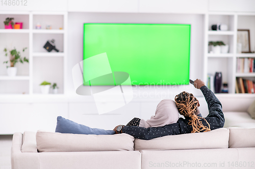 Image of African Couple Sitting On Sofa Watching TV Together