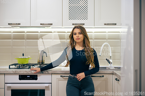 Image of Young woman at luxury white classic kitchen interior