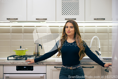 Image of Young woman at luxury white classic kitchen interior