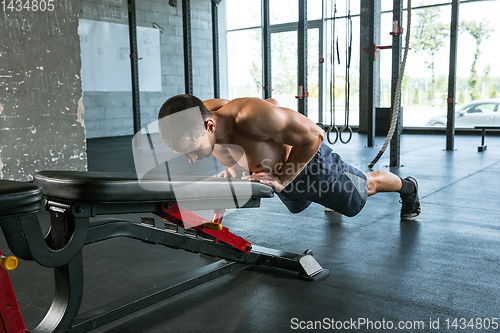 Image of A muscular male athlete doing workout at the gym