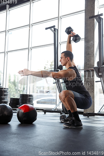 Image of A muscular male athlete doing workout at the gym