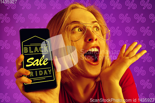 Image of Portrait of woman showing screen of mobile phone, black friday