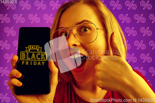 Image of Portrait of woman showing screen of mobile phone, black friday