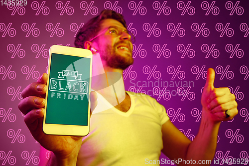 Image of Portrait of man showing screen of mobile phone, black friday