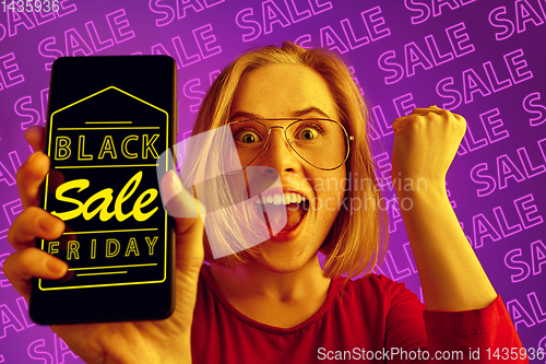 Image of Portrait of woman showing screen of mobile phone, black friday